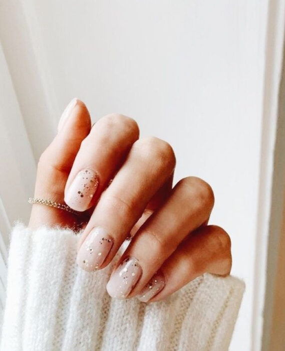 Manicura con fondo color nude y detalles de glitter color plateado