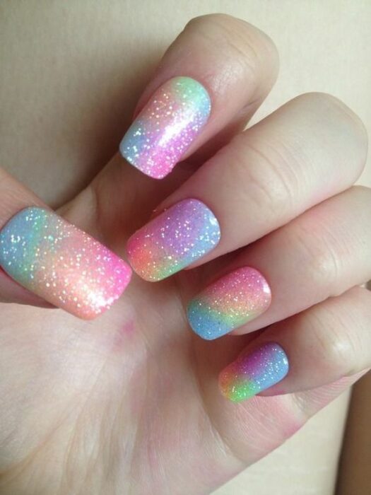 Uñas con fondo de colores arcoíris y detalles de glitter de color plateado