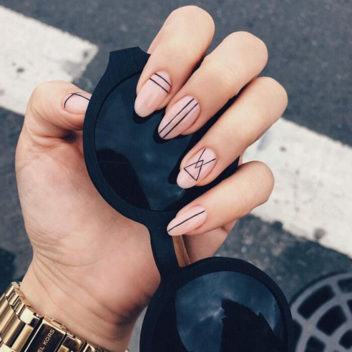 Uñas en base nude con diseño en líneas negras