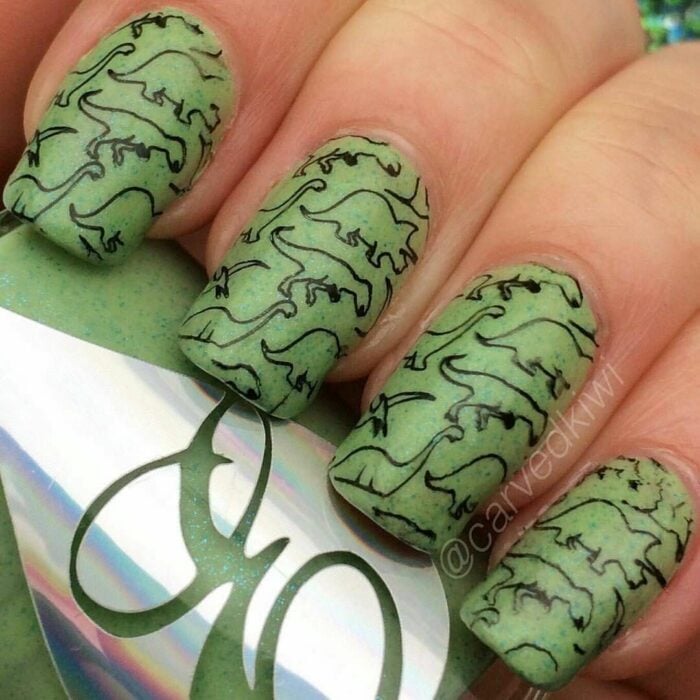 Chica con un diseño de uñas de dinosaurios en diferentes colores 