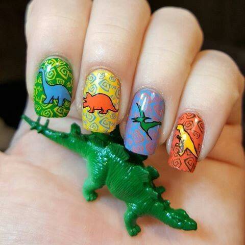 Chica con un diseño de uñas de dinosaurios en diferentes colores 