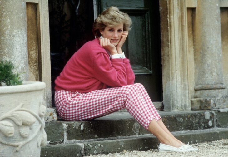 Diana Spencer sentada en las escaleras del palacio usando un outfit de color rosa 