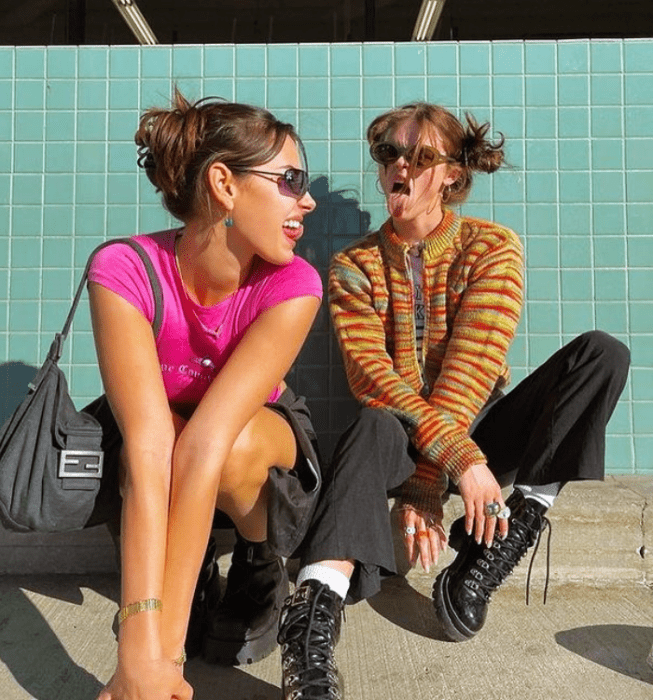 chicas con el cabello corto usando lentes de sol, blusa rosa de manga corta, minifalda negra, pantalones de mezclilla negros, botines negros, bolso oscuro, blusa naranja con amarillo 