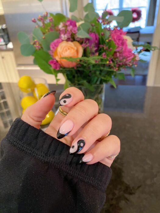 Chica mostrando sus uñas con diseño Yin Yang en color nude con negro 