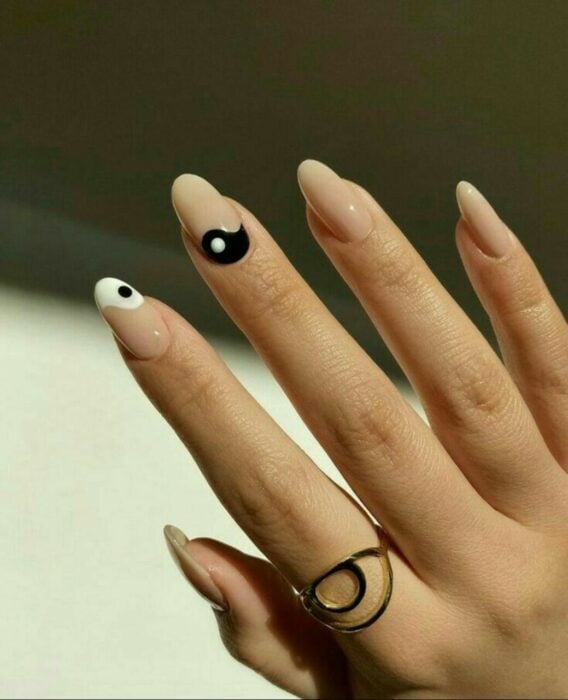Chica mostrando sus uñas con diseño Yin Yang en color blanco, nude y negro 