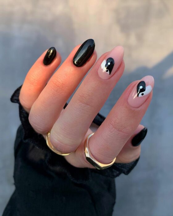 Chica mostrando sus uñas con diseño Yin Yang en color negro con blanco y corazones 