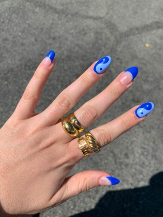 Chica mostrando sus uñas con diseño Yin Yang en colores azules 