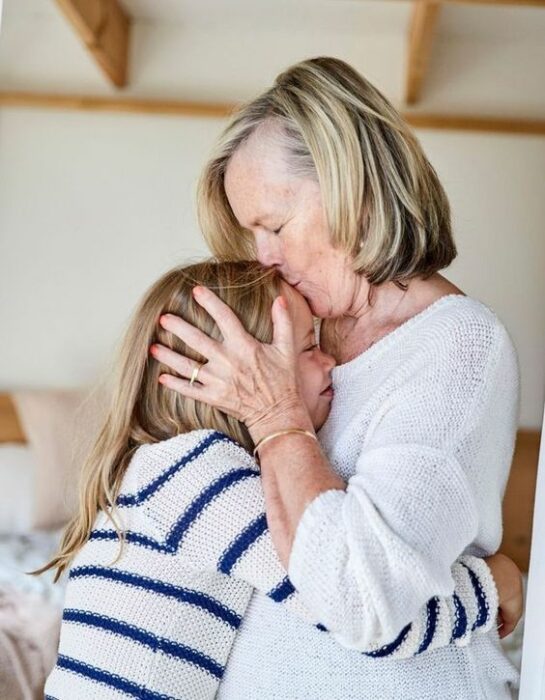 Abuela dando un beso a su nieta en la frente 