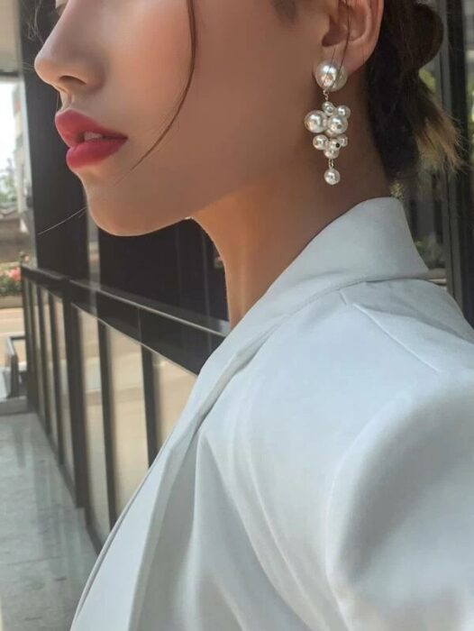 Chica usando unos aretes en forma de perlas 