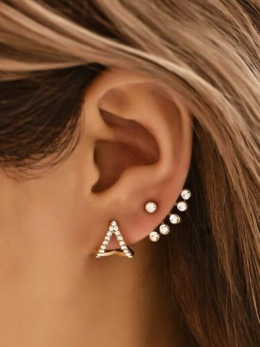 Chica usando unos aretes en forma de triangulo con algunos puntos 