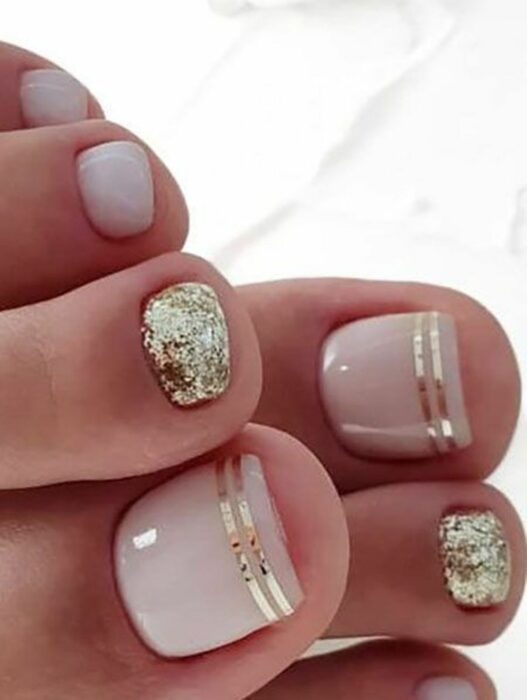 Diseño de uñas para pies en color nude con destellos en dorado 