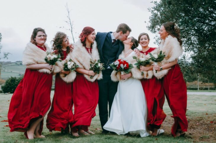 Damas de honor con abrigos durante la sesión de fotos de la boda junto a los novios