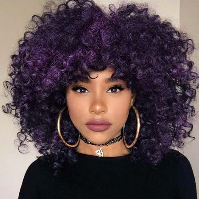 Chica con el cabello rizado y teñido de color purpura 