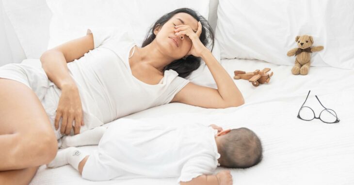 Mujer cerrando los ojos tratando de dormir junto a su hijo; Las mamás son las que menos duermen en la casa