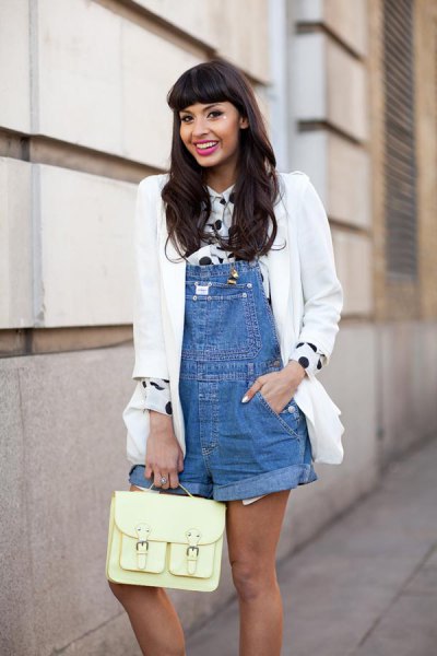 Chica usando un overol con una blusa de color blanco con negro y un saco blanco 