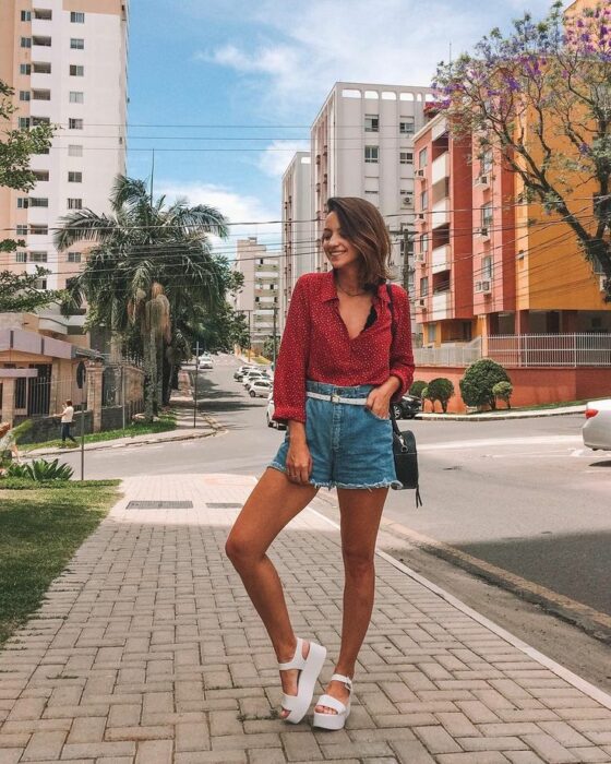 Chica usando shorts de mezclilla, blusa roja y sandalias de plataforma 