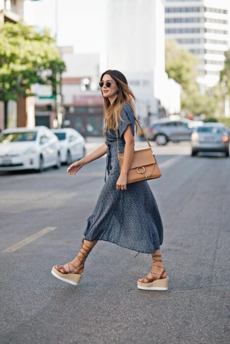 Chica caminando por la calle mientras usa un vestido y sandalias de plataforma 