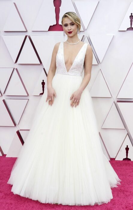 Maria Bakolova en la alfombra roja de los oscar usando un vestido de color blanco 