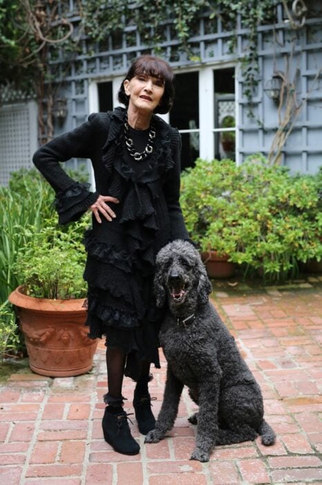 Mujer de la tercera edad vestida de color negro y acompañada de su perro