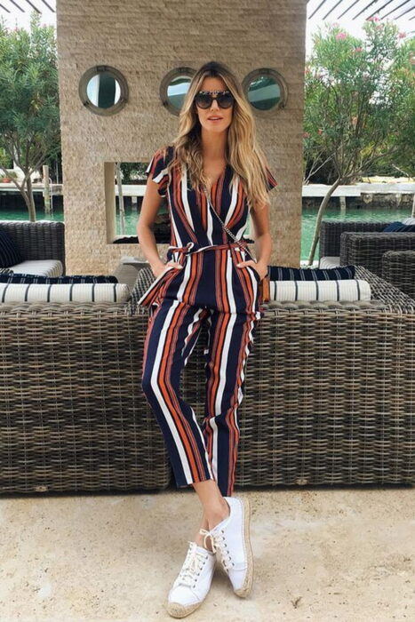 Chica usando un jumpsuit de rayas con unos tenis de color blanco 