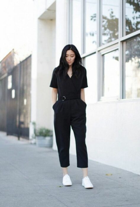 Chica usando un jumpsuit de color negro con tenis de color blanco 