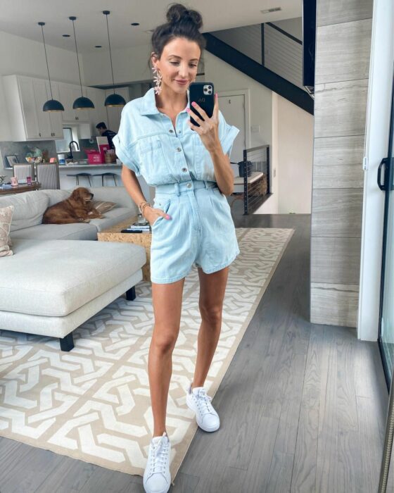 Chica usando un jumpsuit de color mezclilla con tenis blancos  