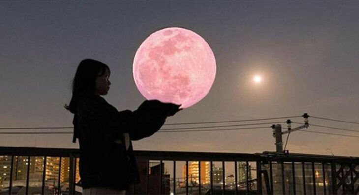 Mujer que aparenta sostener una superluna rosa en sus manos