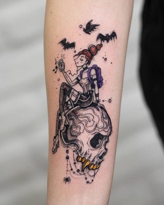 Tatuaje de mujer sentada sobre un cráneo; Tatuaje de Robson Carvalho