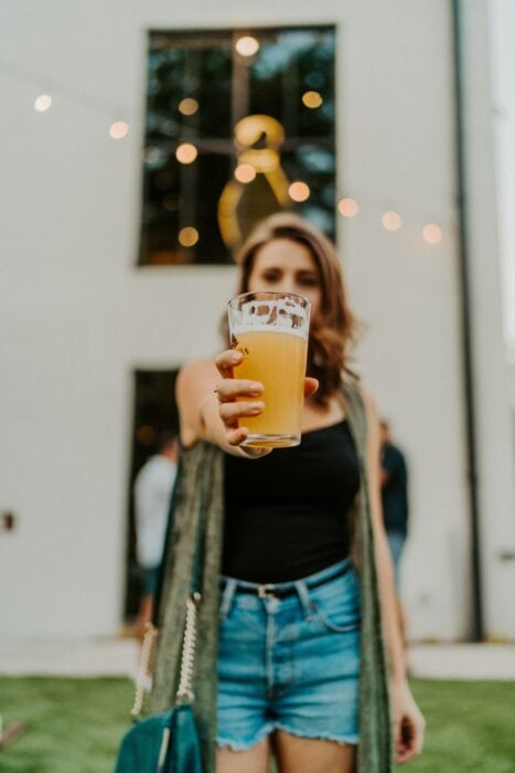 chica sosteniendo un vaso de cerveza clara; Tomar cerveza podría disminuir el riesgo de Alzheimer estudio 