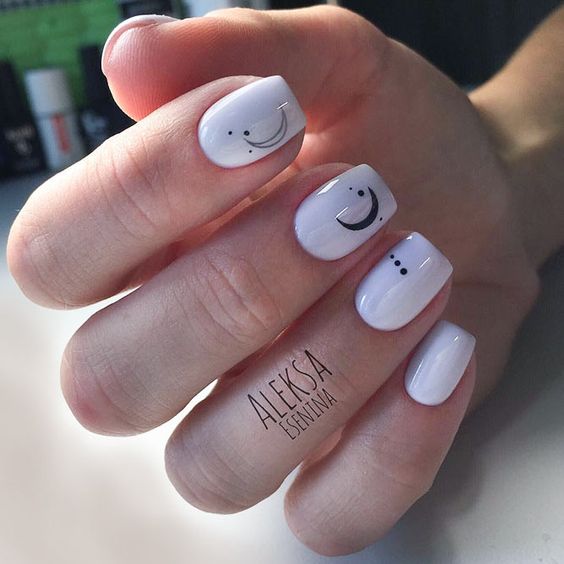 Manicura en tono blanco con luna y puntos negros; Uñas con lunitas que amarás 