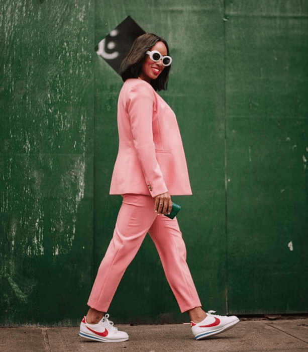 chica morena con lentes de sol blancos, traje rosa, tenis blancos con rosa