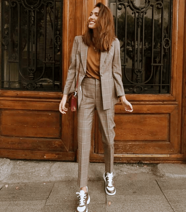 chica de cabello claro con camiseta mostaza, traje gris de cuadros, tenis blancos con beige y café