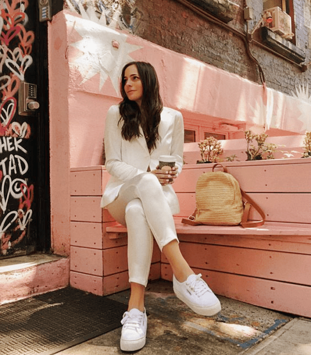 chica de cabello castaño largo con traje blanco, tenis blancos, bolso amarillo claro