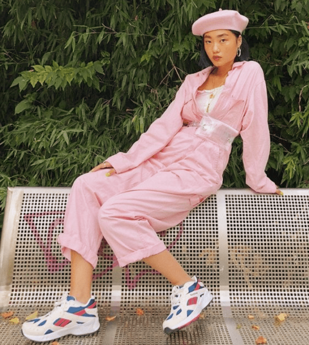 chica de cabello corto usando un top blanco, chaqueta de mezclilla rosa pastel, pantalones rosa pastel holgados, tenis blancos con rosa y azul, beret rosa pastel