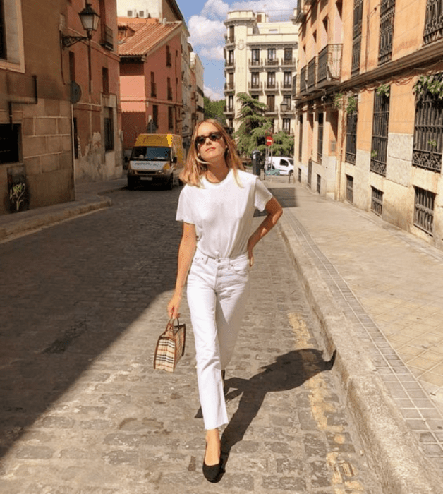 chica rubia con lentes de sol, playera blanca, jeans blancos ajustados y flats negros de cuero