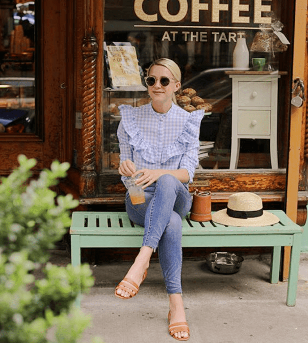 chica de cabello rubio con lentes de sol, blusa azul celeste de cuadros blancos, jeans ajustados y flats beige claro