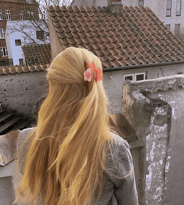 chica rubia con pinza para el cabello rosa coral, suéter gris tejido