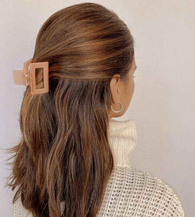 chica de cabello castaño largo usando una pinza para el cabello color rosa coral cuadrada, suéter beige tejido de cuello