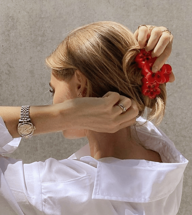 chica rubia usando una pinza para el cabello roja con camisa blanca de vestir y reloj plateado