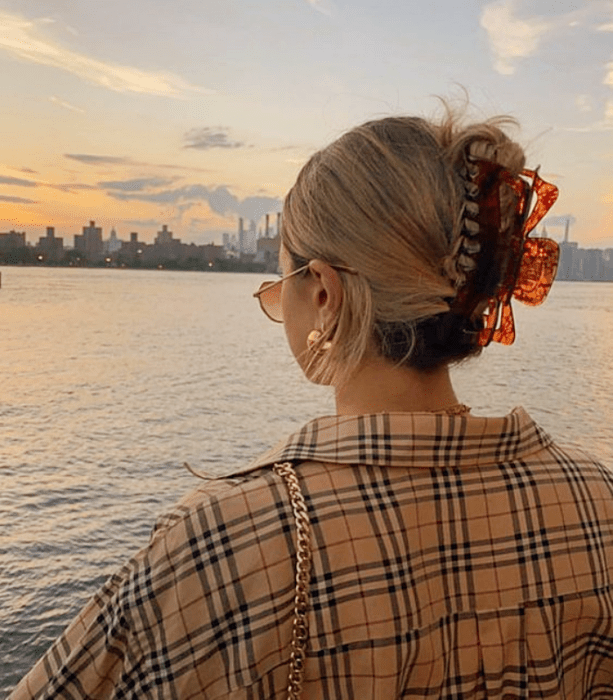 chica rubia con pinza para el cabello color naranja con café, camisa de cuadros beige con líneas azules y rojas