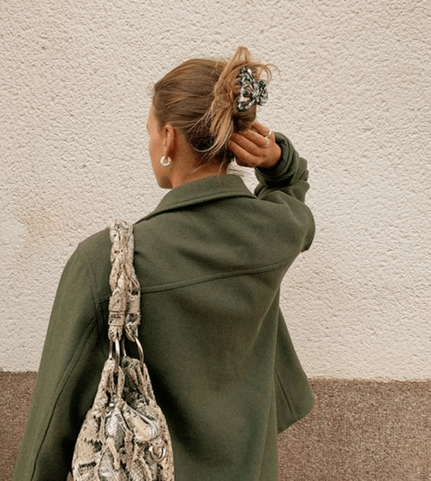 chica rubia con pinza del cabello gris con florecitas, chaqueta verde, bolso beige de animal print 