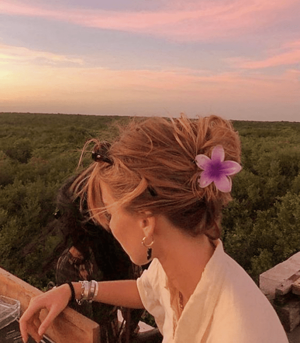 chica rubia con pinza para el cabello color rosa en forma de flor, camisa blanca de manga corta