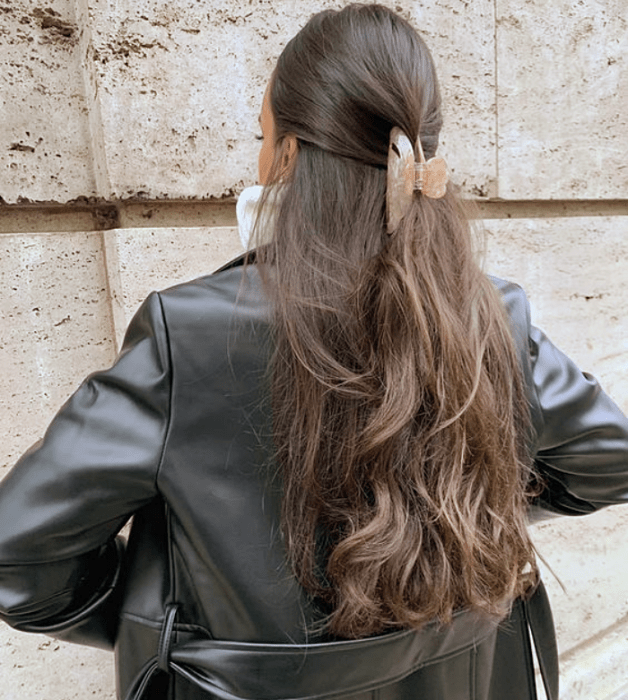 chica de cabello largo castaño usando una pinza para el cabello rosa pastel, chamarra de cuero negra