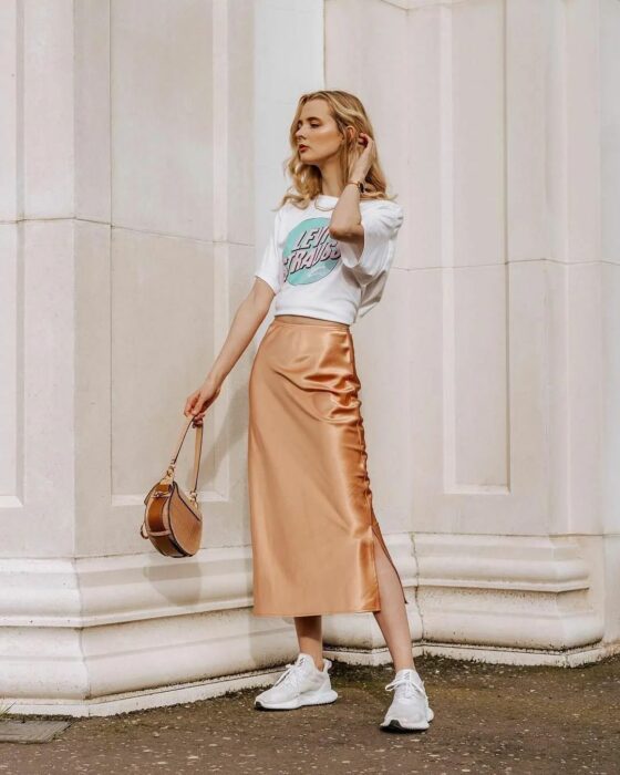 Chica usando una falda de satín en color beige con blusa blanca