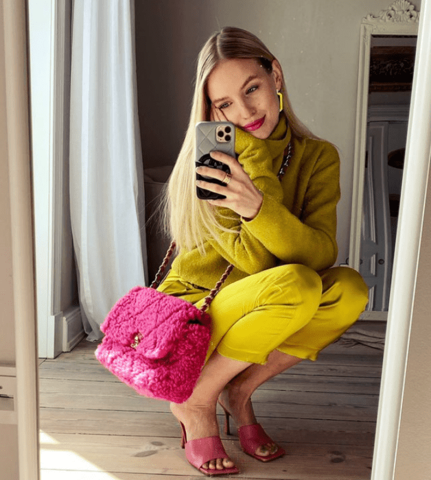 chica rubia con traje de vestir amarillo mostaza, bolso rosa fucsia, tacones sandalias de tacón rosa