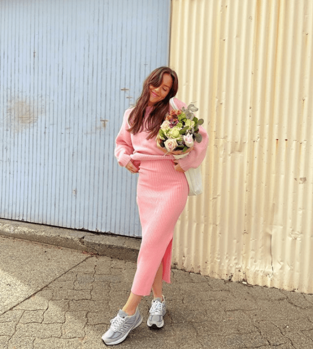 chica de cabello castaño largo usando un vestido tejido rosa ajustado, tenis blancos con gris y flores