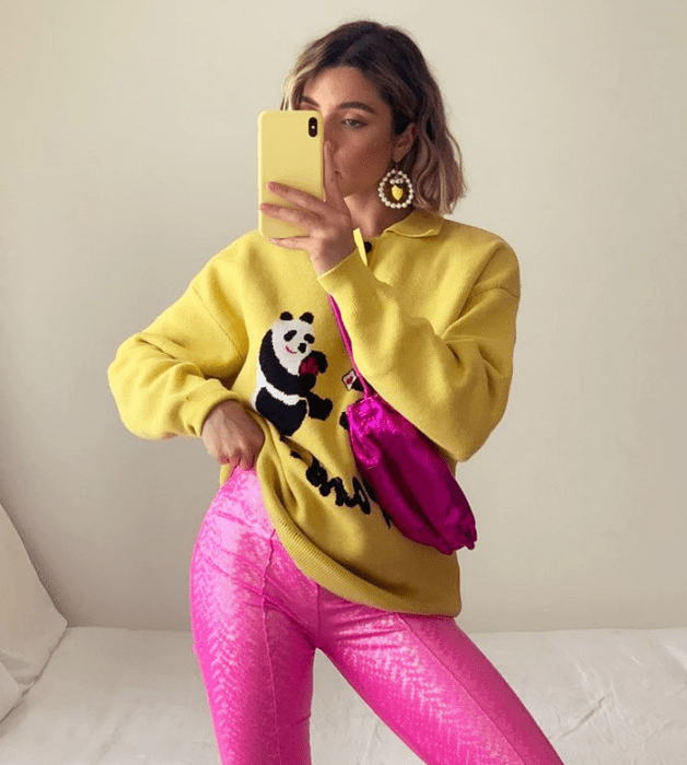 chica de cabello claro con sudadera amarilla con panda, leggings rosas neón, bolso rosa fucsia