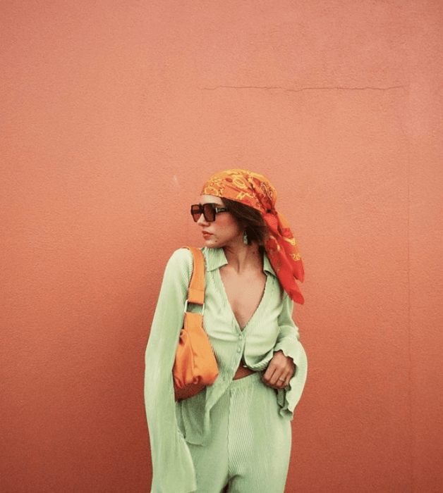 chica de cabello oscuro, lentes de sol oscuros, blusa verde pistache, pantalones holgados pistache, bolso naranja de piel