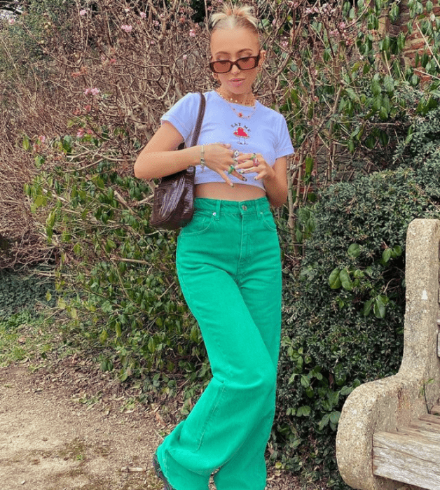 chica rubia con lentes de sol, crop top blanco, pantalones verdes holgados, bolso oscuro de piel pequeño