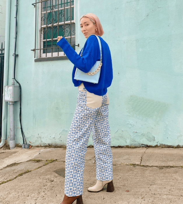 chica de cabello rubio corto con suéter azul brillante, pantalón blanco con azul, botines beige con café y bolso celeste